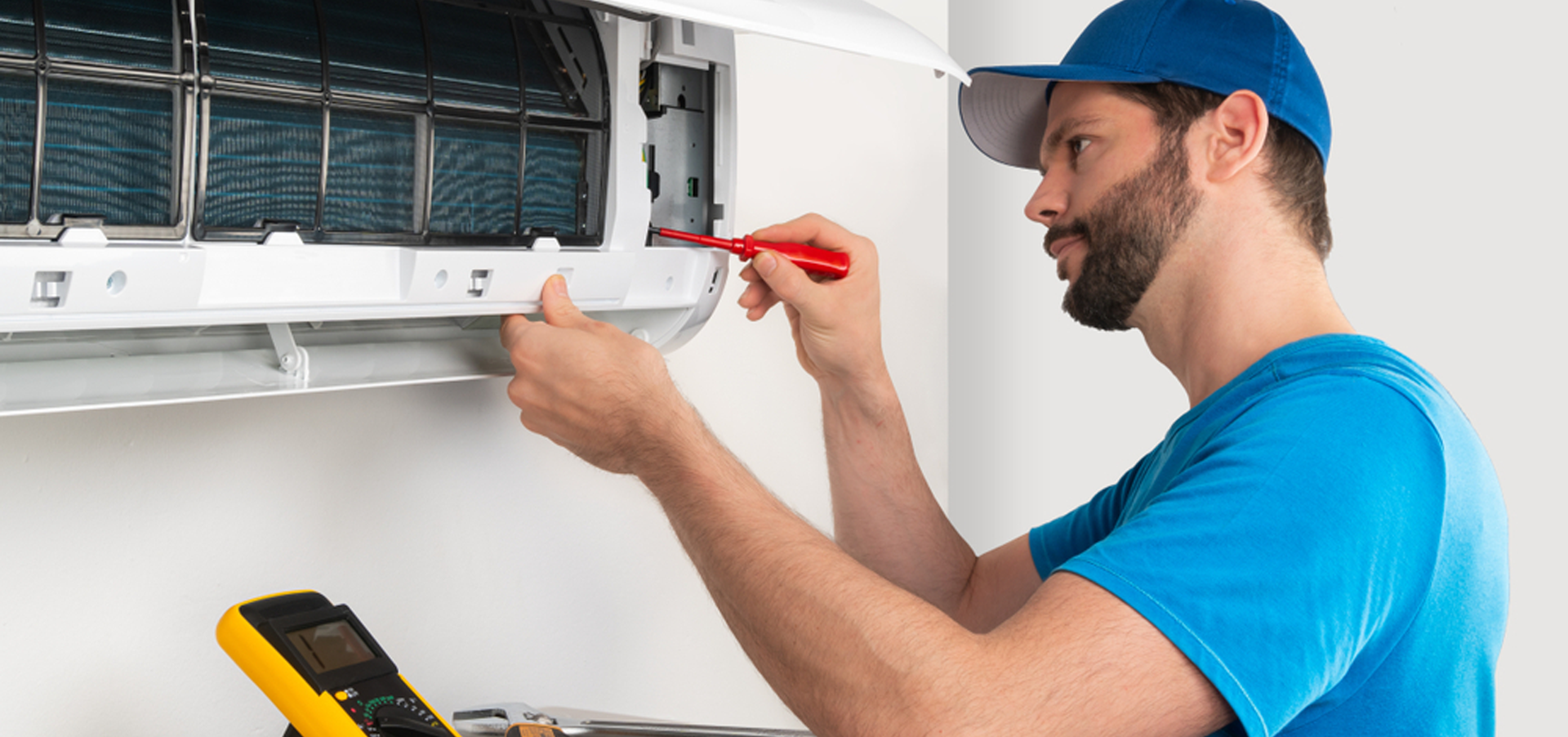 Engineer inspecting the indoor air conditioning unit filter during maintenance